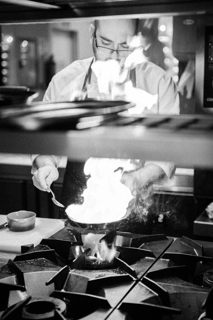 Cocinero de La Colosal cocinando un plato en una sartén en llamas.