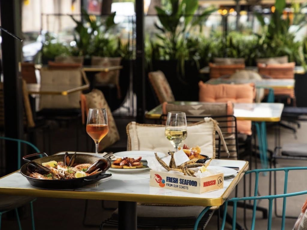 Terraza del restaurante la colosal con dos copas de vino y comida mediterranea en la mesa
